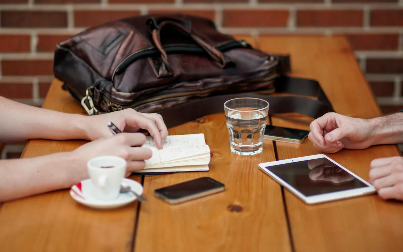 Phone, tablet, coffee and notebook on a wooden table during a meeting