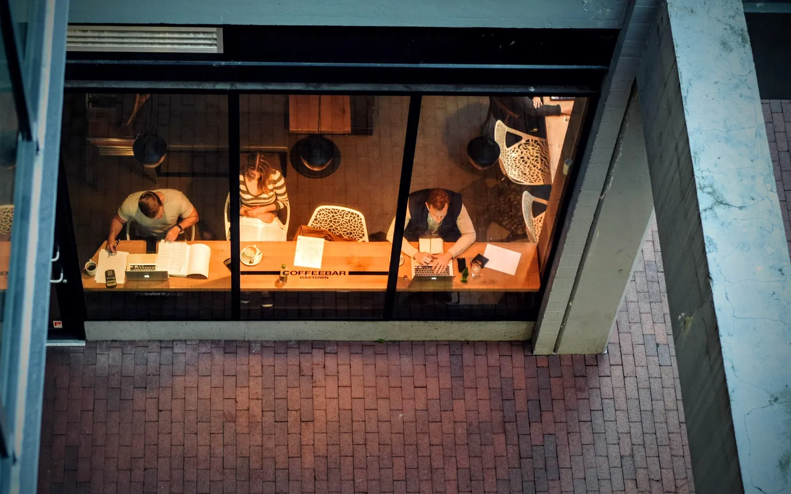 Overhead view through a café window of people working at laptops