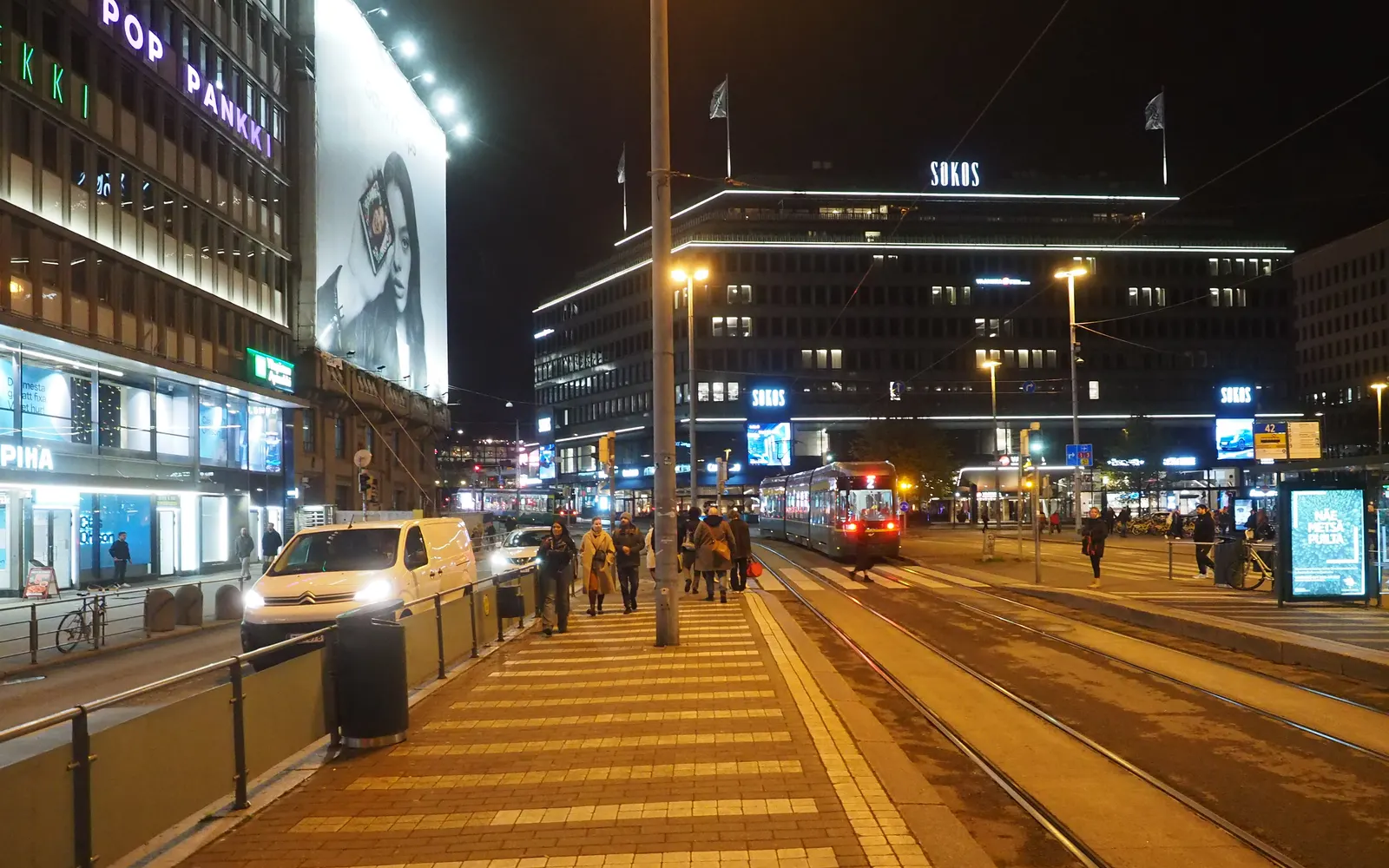 Commuters walking along a city tram stop in the evening