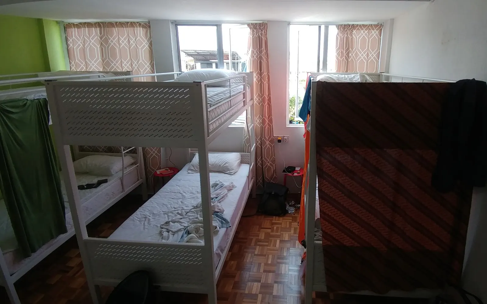 Hostel dorm room with white metal bunk beds and a backpack on the floor