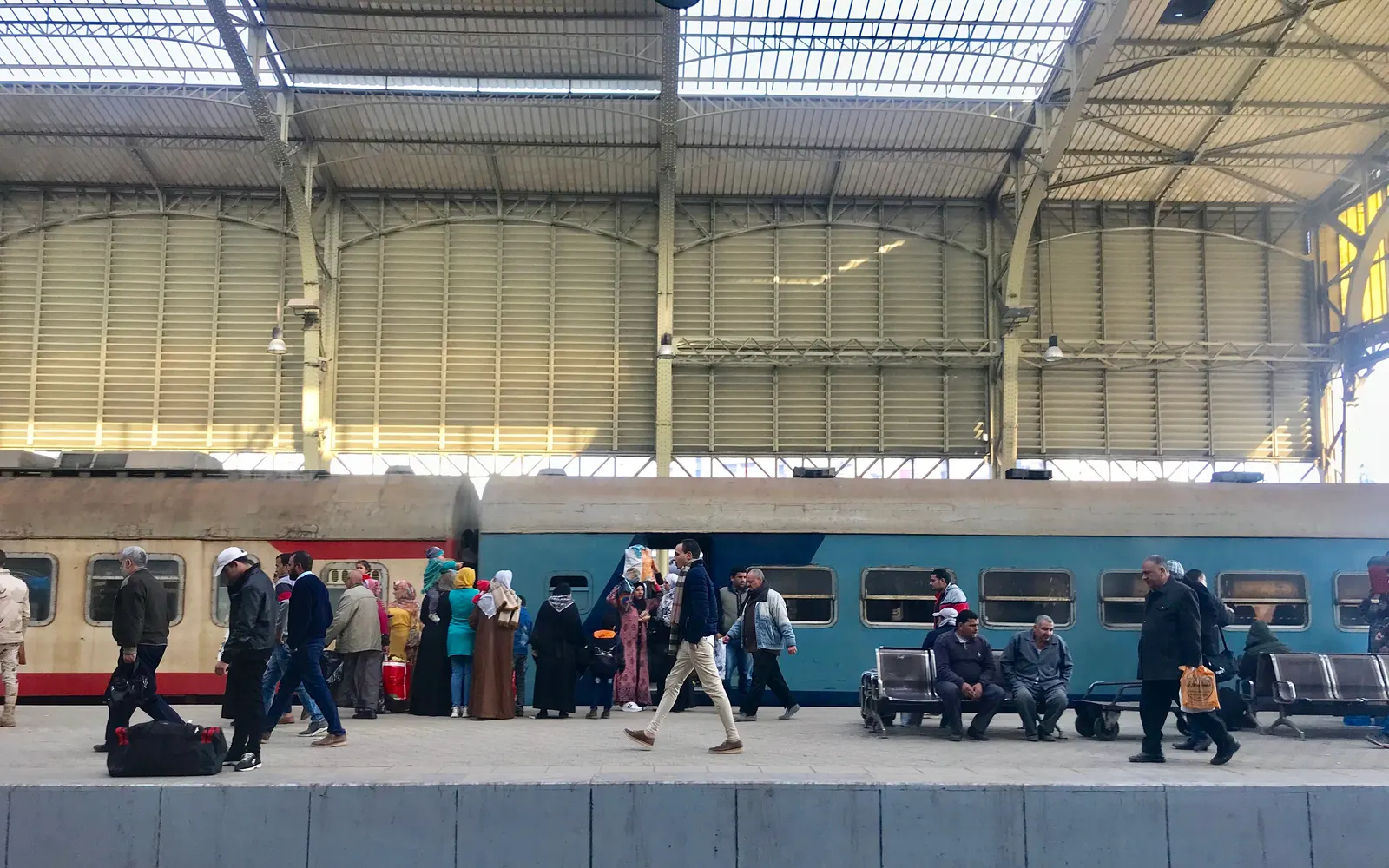 Commuters walking and waiting on a railway station platform beside a train